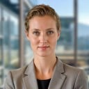 a female in grey business attire standing her back to the builing view window