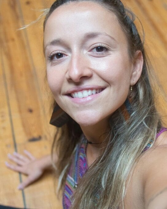 a female with long curly hair lying on the wooden ground and looking into the camera