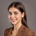 a female with long hair in the brown business suit standing sideways