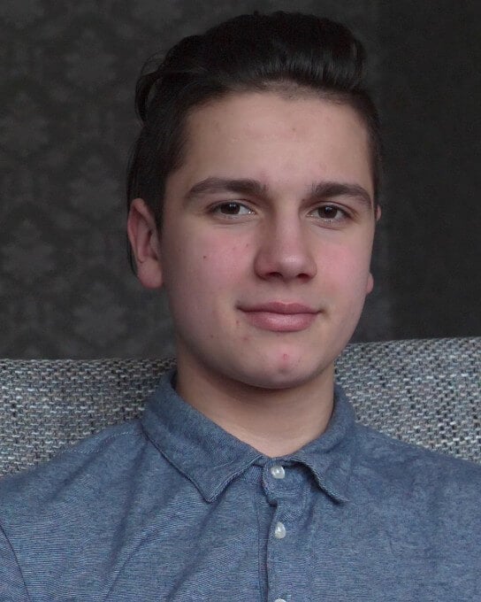 a man in a blue blouse sitting on a couch.