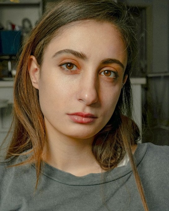a woman with long brown hair in the dark grey shirt