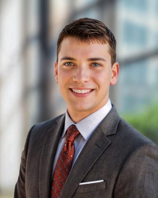 AI generated LinkedIn headshot of a man with dark business suite and red tie standing his sideways 