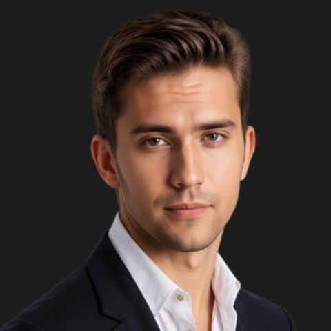 headshot of a man in a professional suit standing sideways with a black backdrop