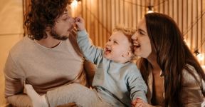 Young parents laughing heartily while holding a baby