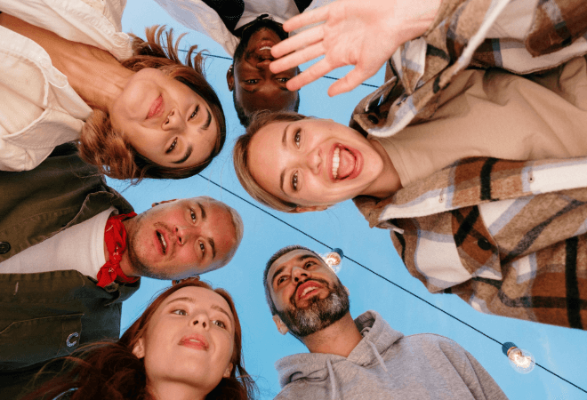 Group of three men and three women smiling and waving at the camera